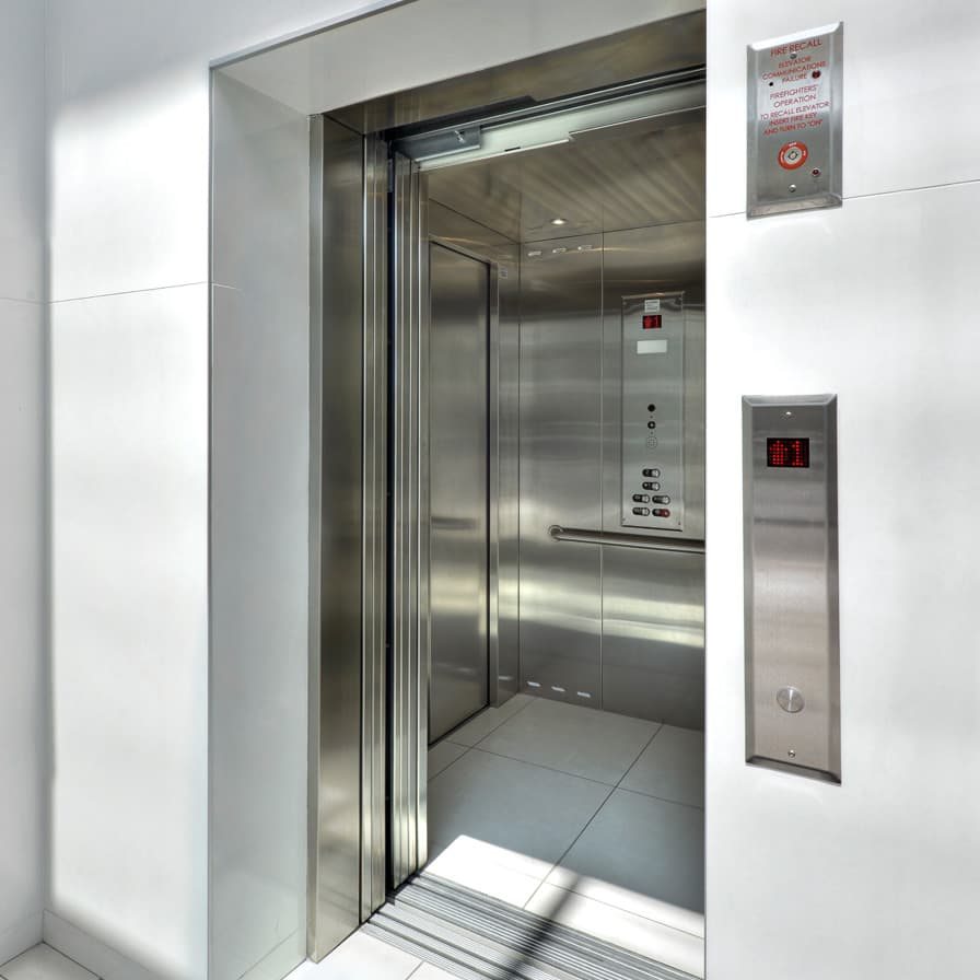 Stainless steel home elevator cab at an open landing
